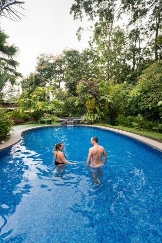 a man and woman standing in a swimming pool at Catarata Eco Lodge in Fortuna
