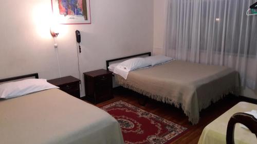 a bedroom with two beds and a rug at Hostal Santa María Gracia in Quito
