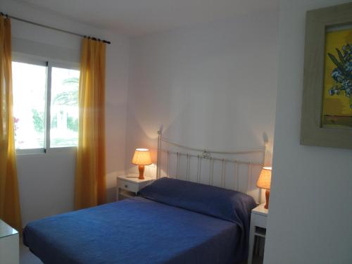 1 dormitorio con cama con sábanas azules y ventana en apartamento DENIA. en Dénia