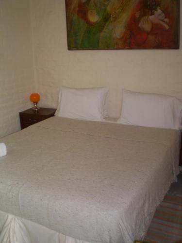 a bedroom with a bed with white sheets and a painting at Palermo Viejo Bed & Breakfast in Buenos Aires