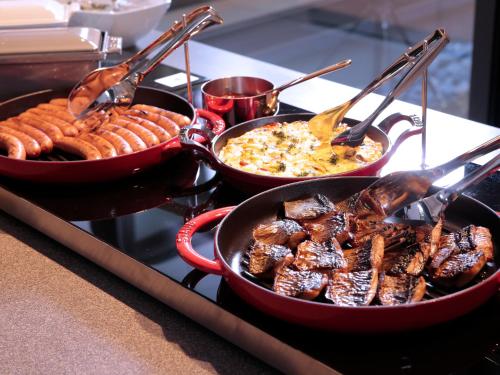 a stove with two pans of food and some sausages at Hotel Intergate Kyoto Shijo Shinmachi in Kyoto