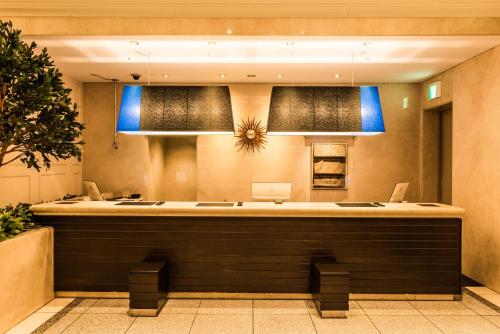 a lobby with a large counter with blue lights at HOTEL MYSTAYS PREMIER Omori in Tokyo