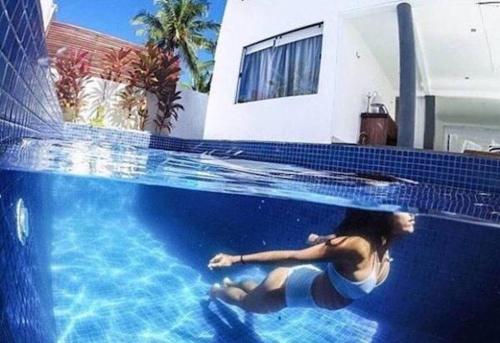 a woman laying in the water in a swimming pool at Blanc Residence in Pipa