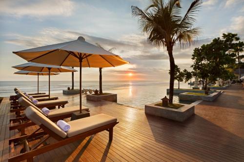 a group of chairs and umbrellas on a beach at The Seminyak Beach Resort & Spa in Seminyak