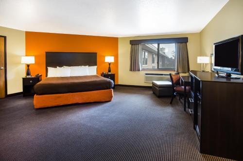 a hotel room with a bed and a flat screen tv at AmericInn by Wyndham Menomonie in Menomonie