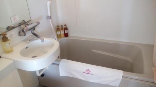 a bathroom with a sink and a bath tub at Hotel Sun Queen in Naha