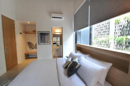 a bedroom with a bed with white pillows and a window at The Nest House in Melaka
