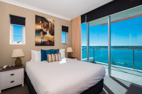 a bedroom with a large white bed and a large window at Silvershore Apartments on the Broadwater in Gold Coast