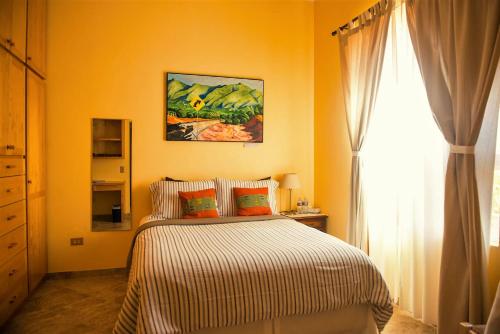 a yellow bedroom with a bed and a window at Quinta Estrella in Valle de Guadalupe