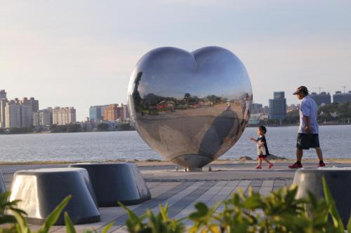 a man and a child walking past a large heart sculpture at Lienmei 月租房 in Taipei