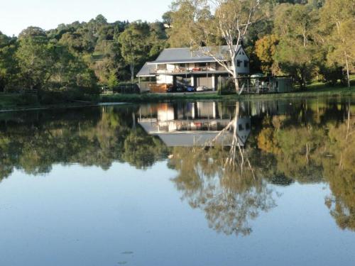 a house on a lake with its reflection in the water at Samford Lakes Rural Accommodation in Mount Samson
