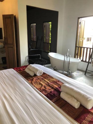 a bed with two towels and a bath tub at Moonlight Champa Riverview in Luang Prabang