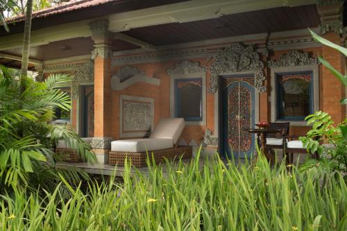 a porch of a house with a couch and a table at Puri Santrian Beach Resort And Spa in Sanur