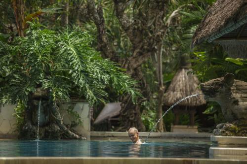 a man in the water with a fountain at Puri Santrian Beach Resort And Spa in Sanur
