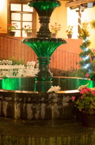 a green glass fountain in a building with flowers at La Casona de los Gómez in Zacatlán