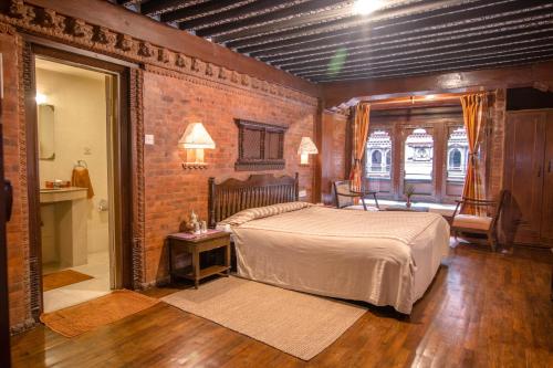 a bedroom with a bed and a brick wall at Kantipur Temple House in Kathmandu