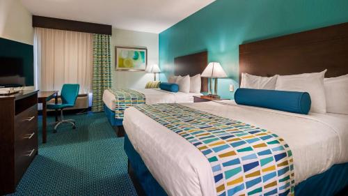 Best Western Plus Blue Angel Inn في بينساكولا: غرفة فندقية بسريرين ومكتب