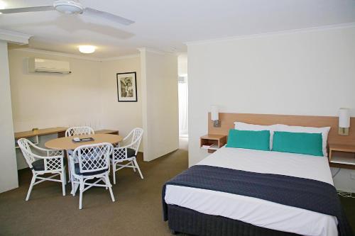 1 dormitorio con 1 cama, mesa y sillas en Darcy Arms Hotel Motel, en Gold Coast