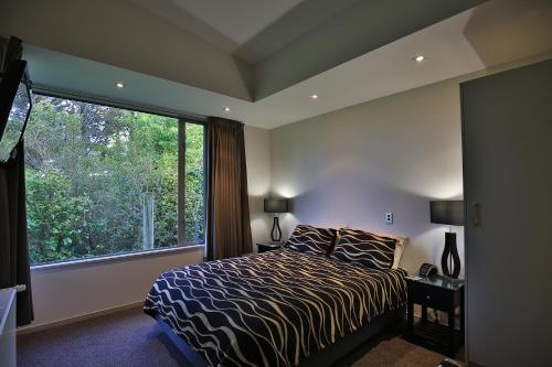 a bedroom with a bed and a large window at The Links Carters Beach Apartments in Carters Beach