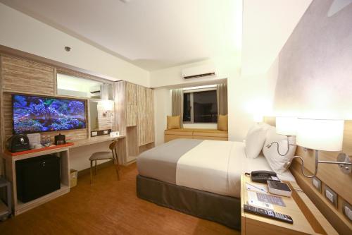 a hotel room with a bed and a flat screen tv at TRYP by Wyndham Mall of Asia Manila in Manila