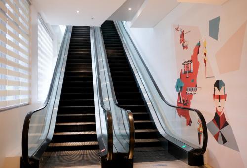 an escalator in a building with a mural on the wall at TRYP by Wyndham Mall of Asia Manila in Manila