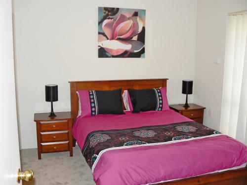 Geraldton Luxury Retreat 2 with free Streaming في جيرالدتون: غرفة نوم بسرير وردي مع مواقف ليلتين