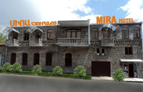 ein großes Steingebäude mit einem Schild darauf in der Unterkunft Hotel MIRA in Goris