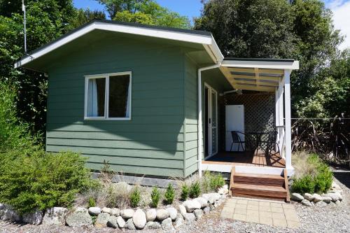 a green tiny house with a porch and a deck at Abel Tasman Haven in Marahau
