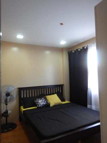 a bedroom with a black bed with a window at Alta Cielo in The Courtyards Baguio in Baguio
