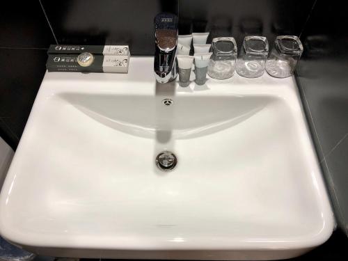 a white sink in a bathroom with glasses on it at Lemongo Youth Hostel Hohhot in Hohhot