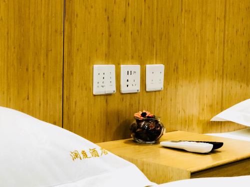 a room with two beds and a table with a vase on it at Lemongo Youth Hostel Hohhot in Hohhot