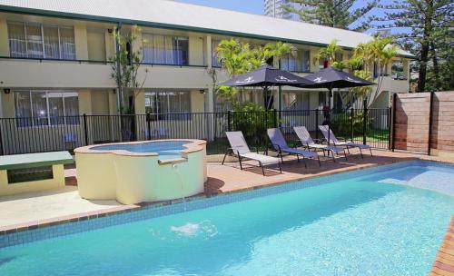a swimming pool with chairs and umbrellas next to a building at Darcy Arms Hotel Motel in Gold Coast