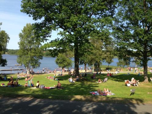 a group of people sitting in the grass by the water at Eksjö Camping & Konferens in Eksjö