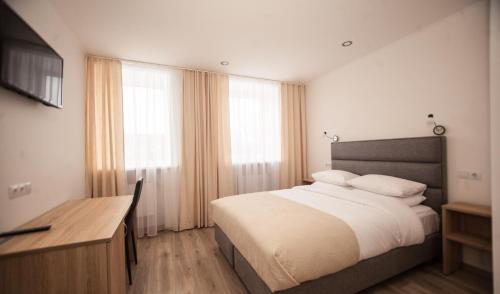 a bedroom with a bed and a desk and windows at Biplan Hotel in Daugavpils