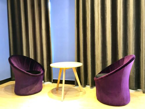 two purple chairs and a table in a room at Lemongo Youth Hostel Hohhot in Hohhot