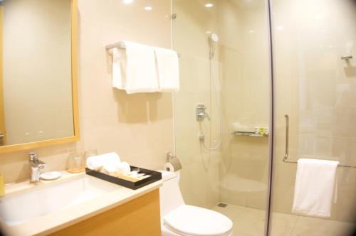 a bathroom with a toilet and a glass shower at Sunshine Apartment in 5* resort in Da Nang
