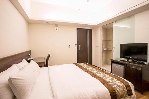 a hotel room with a bed and a flat screen tv at Huang Shin Business Hotel-Chung Kang in Taichung