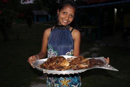 a woman holding a tray of chicken on a plate at 4 Pohon - Les 4 Arbres in Pandang