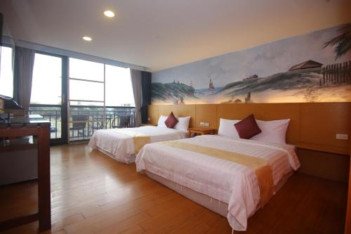 墾丁的住宿－墾丁水岸海景渡假旅店，酒店客房设有两张床,墙上挂有绘画作品