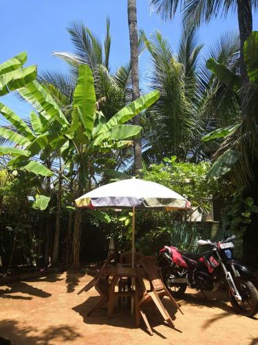 a motorcycle parked under an umbrella next to a picnic table and an umbrella at Alass Ga For Pets Lovers in Trincomalee
