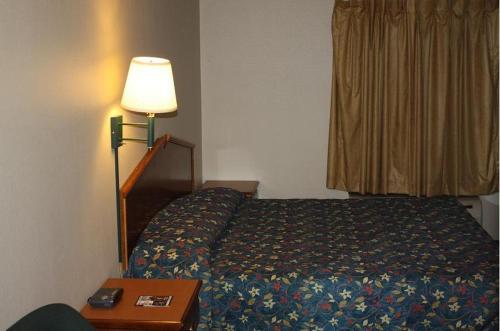 a bedroom with a bed and a lamp and a table at Emerald Inn in Maplewood