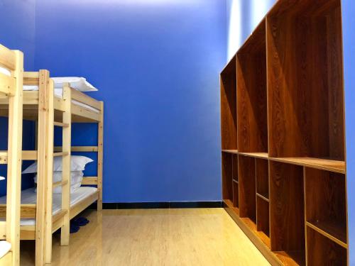 a room with two bunk beds and a blue wall at Lemongo Youth Hostel Hohhot in Hohhot