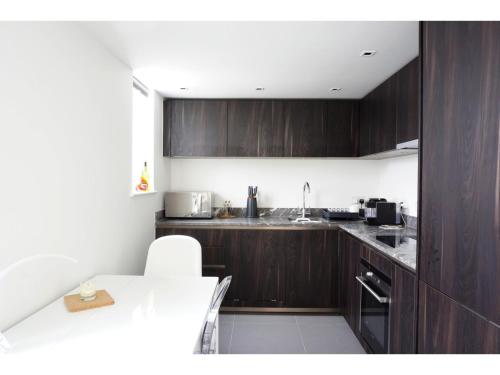 cocina con armarios de madera y encimera blanca en Modern, Spacious 2BR Flat in Oxford en Oxford