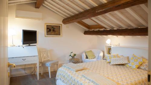 Un dormitorio con una cama, un escritorio y un televisor. en Barone Rosso Suite, en Rávena