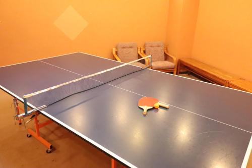 a ping pong table in a room with two chairs at Sado Resort Hotel Azuma in Sado