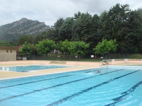 une grande piscine avec des arbres et une montagne dans l'établissement Les Asphodèles, à Saint-Hippolyte-du-Fort
