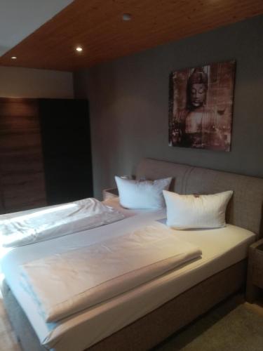 a bed with white sheets and pillows in a room at Hotel Altes Badehaus in Bad Dürrenberg