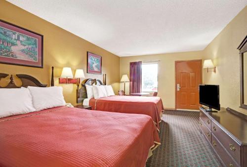 a hotel room with two beds and a flat screen tv at Travelodge by Wyndham Forest Park Atlanta South in Forest Park