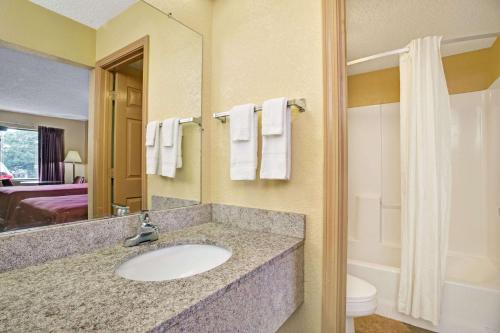 a bathroom with a sink and a toilet and a mirror at Travelodge by Wyndham Forest Park Atlanta South in Forest Park