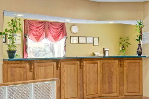 a kitchen with wooden cabinets and a window with red curtains at Travelodge by Wyndham Forest Park Atlanta South in Forest Park